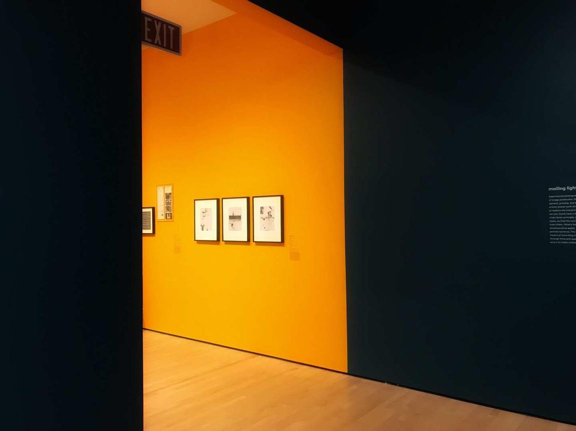 An orange gallery wall seen through a dark doorway