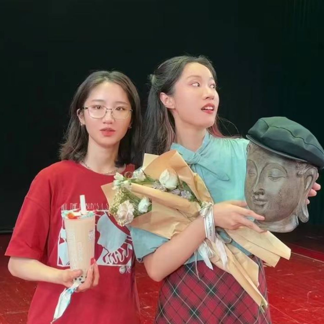 Ruyue Chen backstage on closing night, holding flowers beside a sculpted head prop